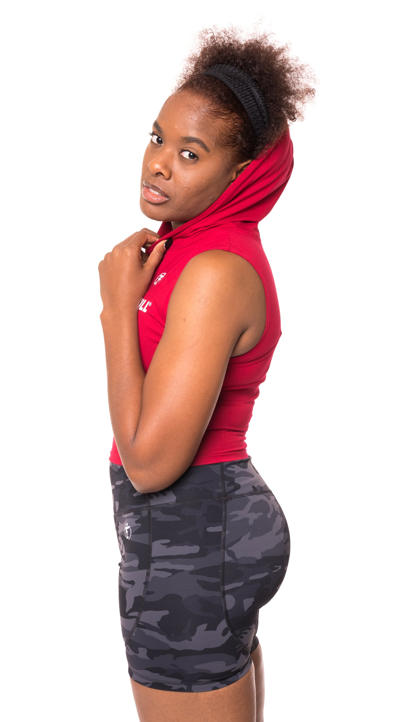 Woman wearing red sleeveless hoodie and camo print high-waisted athletic shorts.