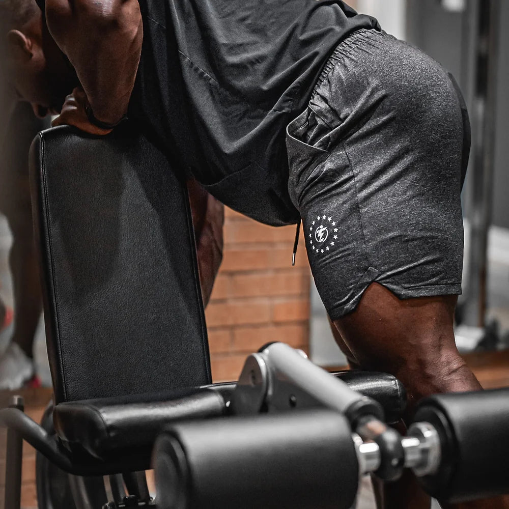 Man wearing gray athletic shorts with logo at gym.