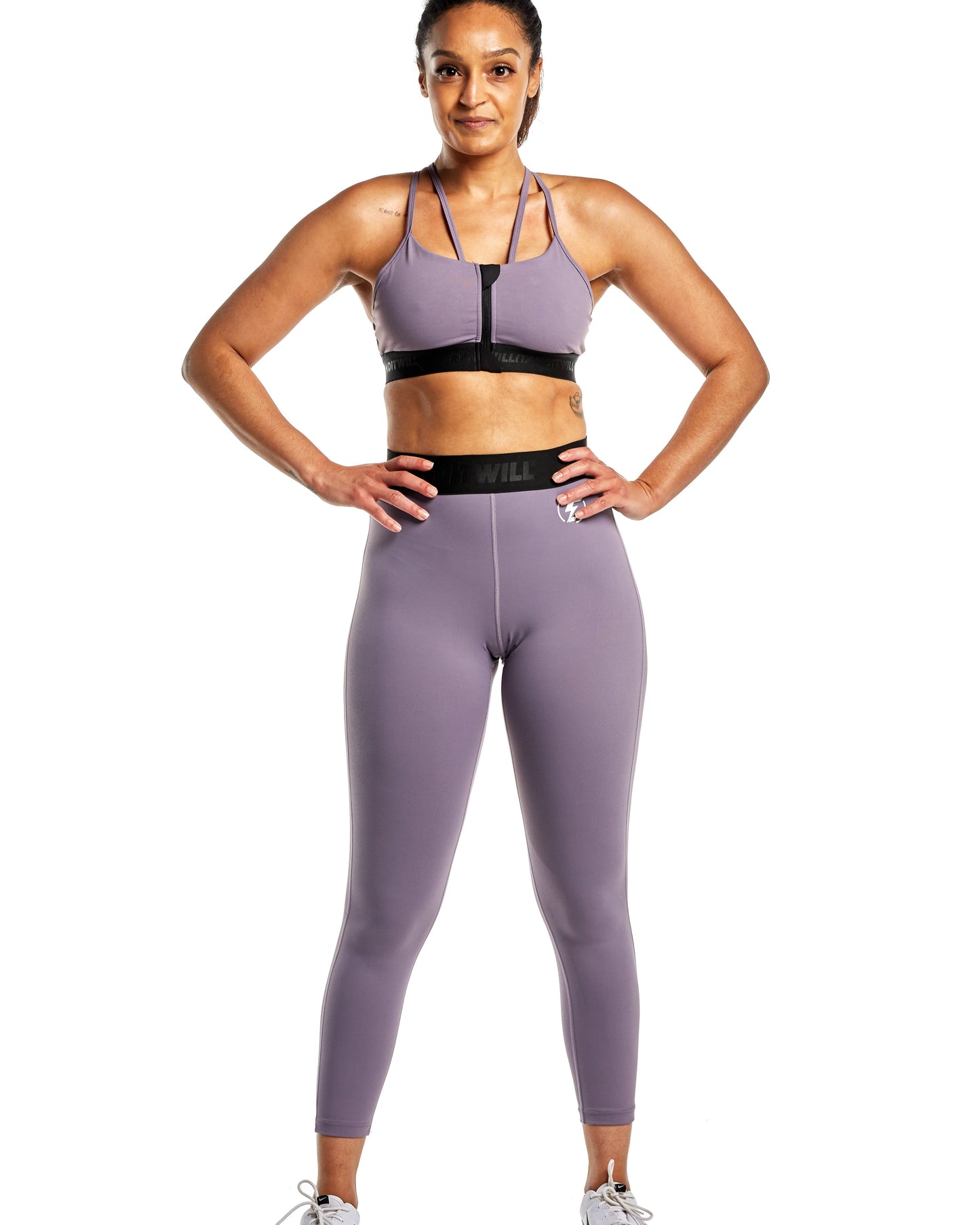 Woman in purple workout set featuring a zip-front sports bra and high-waisted leggings.