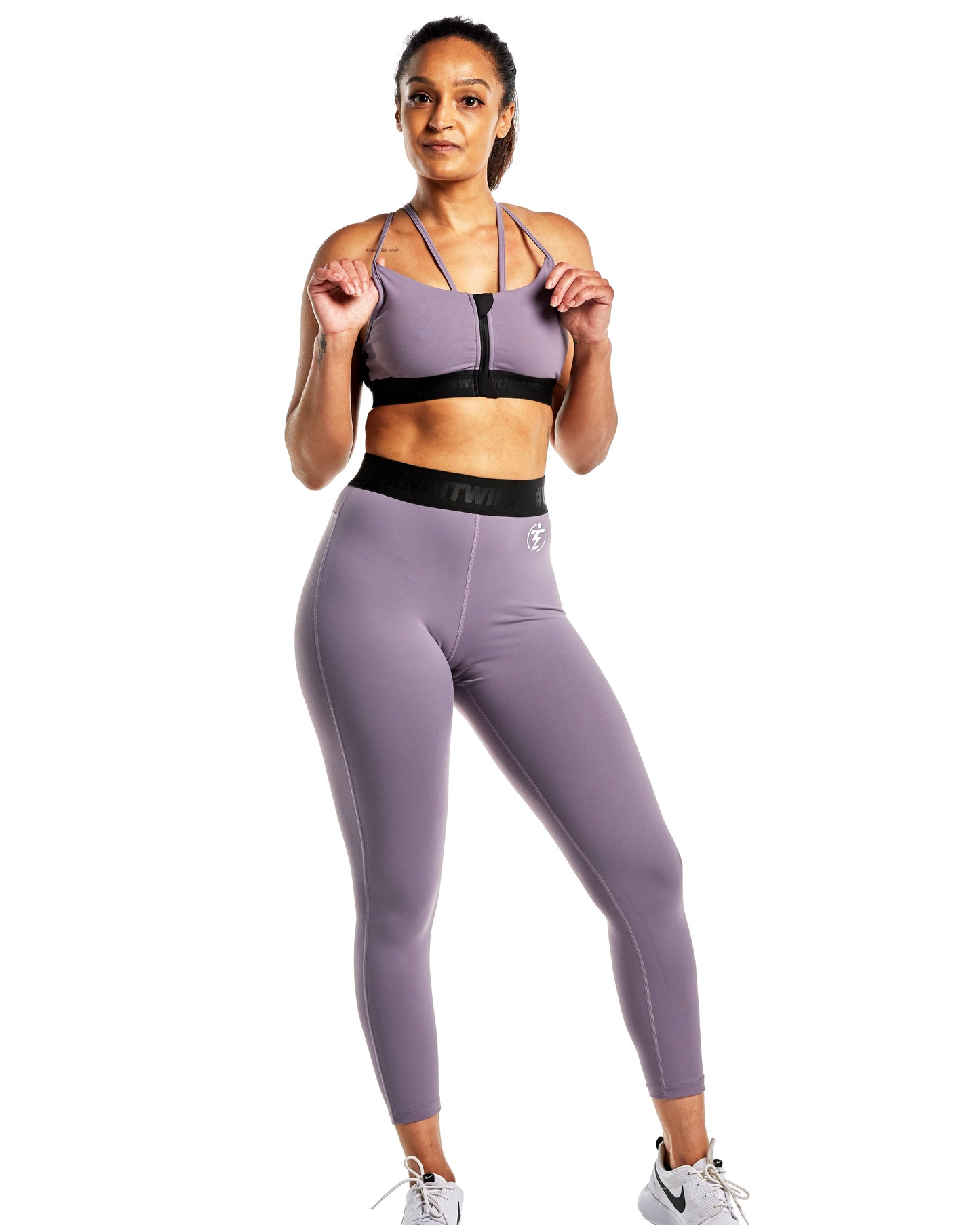 Woman in purple TWINZZ athletic wear set including leggings and zip-up sports bra.