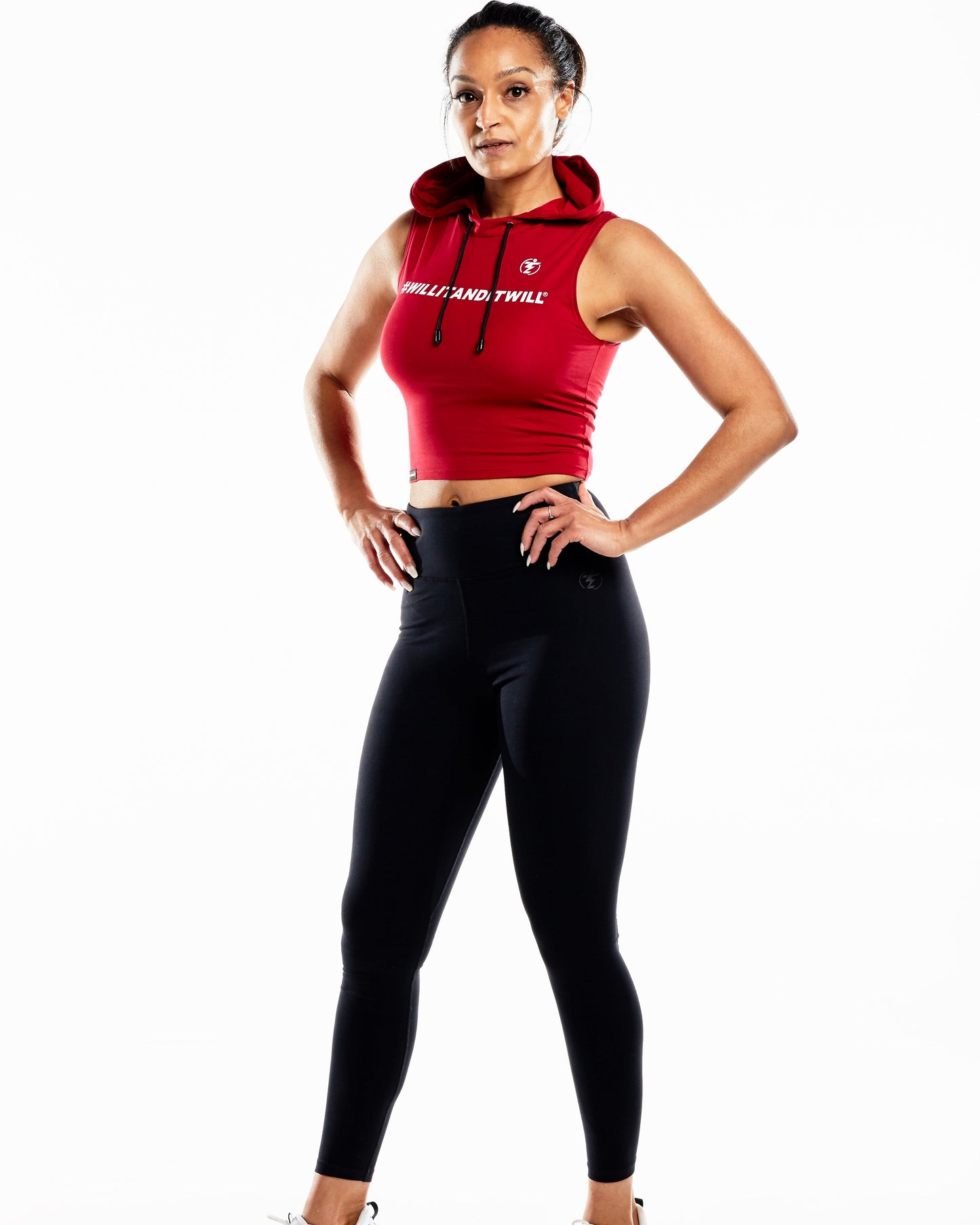 Woman in red cropped hooded tank top and black leggings fitness outfit.