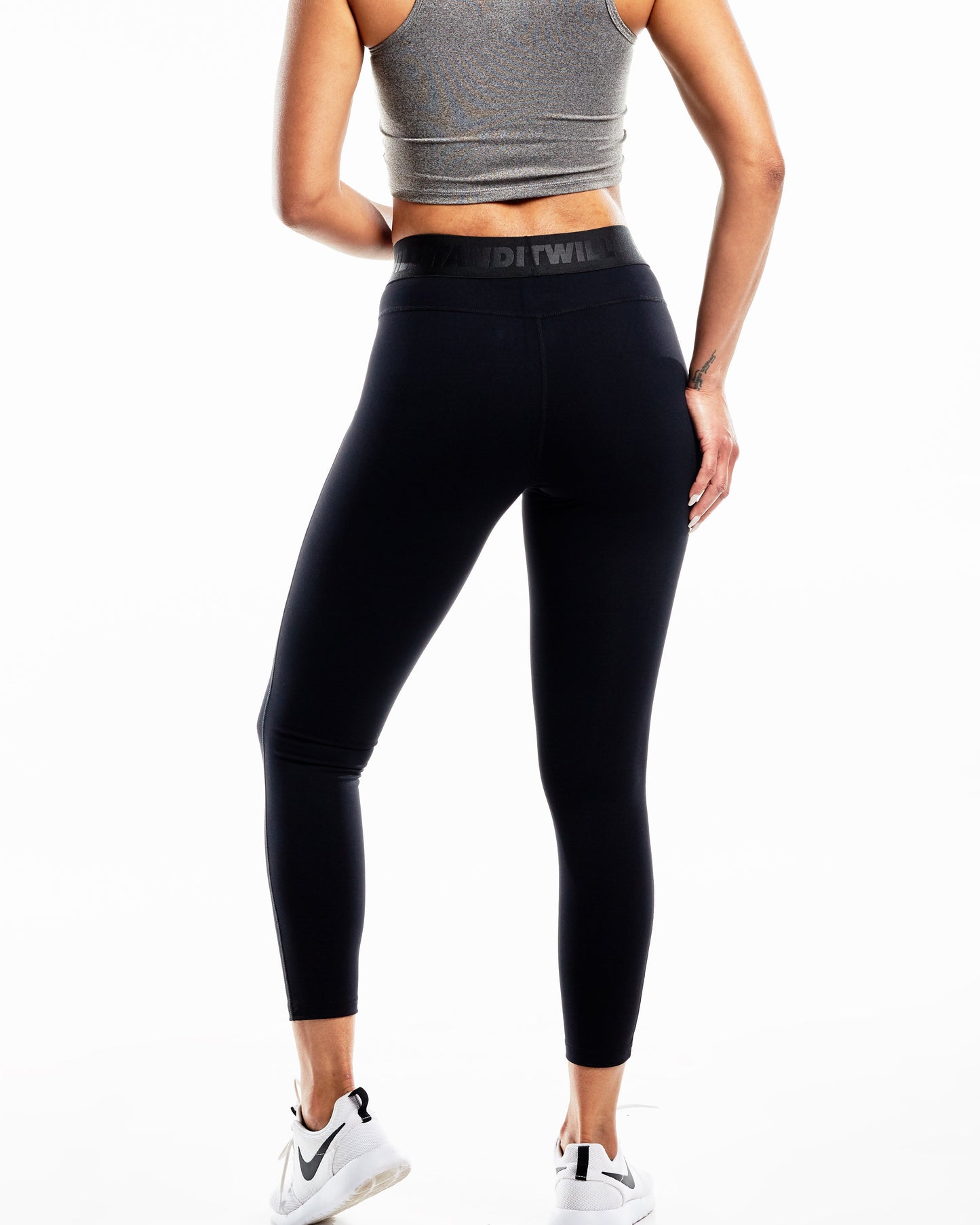 Back view of woman wearing black Band Twill leggings and grey sports bra.