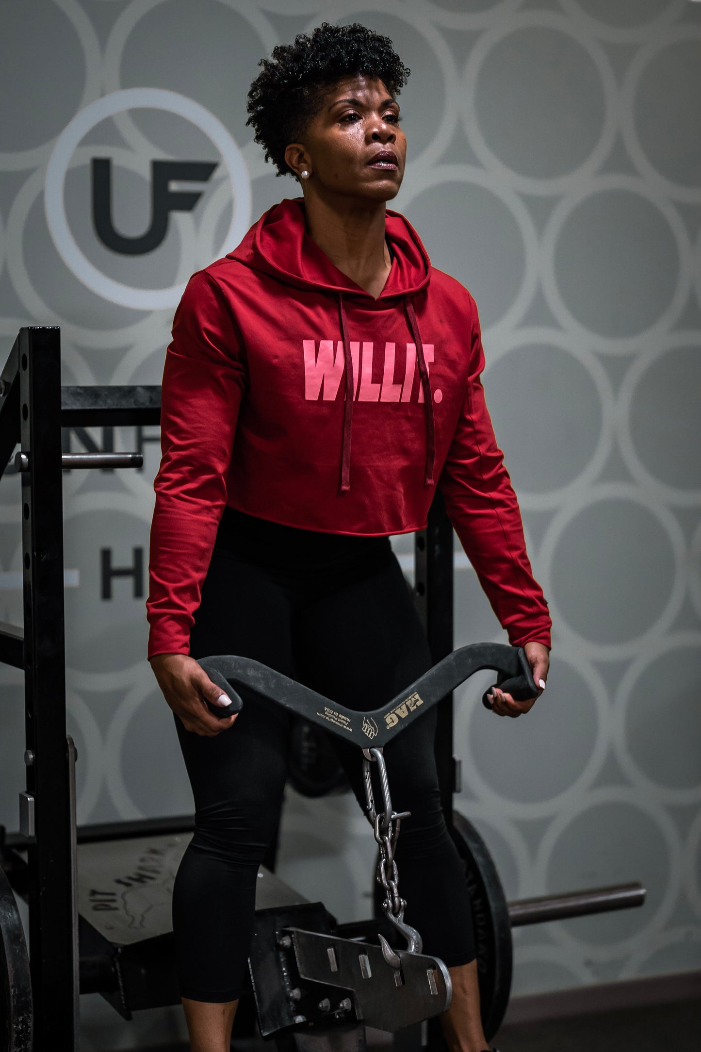 Woman in red hoodie using a MAG grip during a lat pulldown at the gym. Gym fitness training equipment.