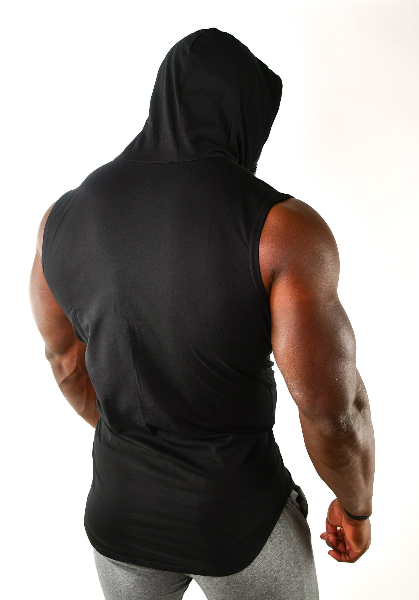 Back view of a man wearing a black hooded sleeveless shirt, showcasing athletic build and gym wear.