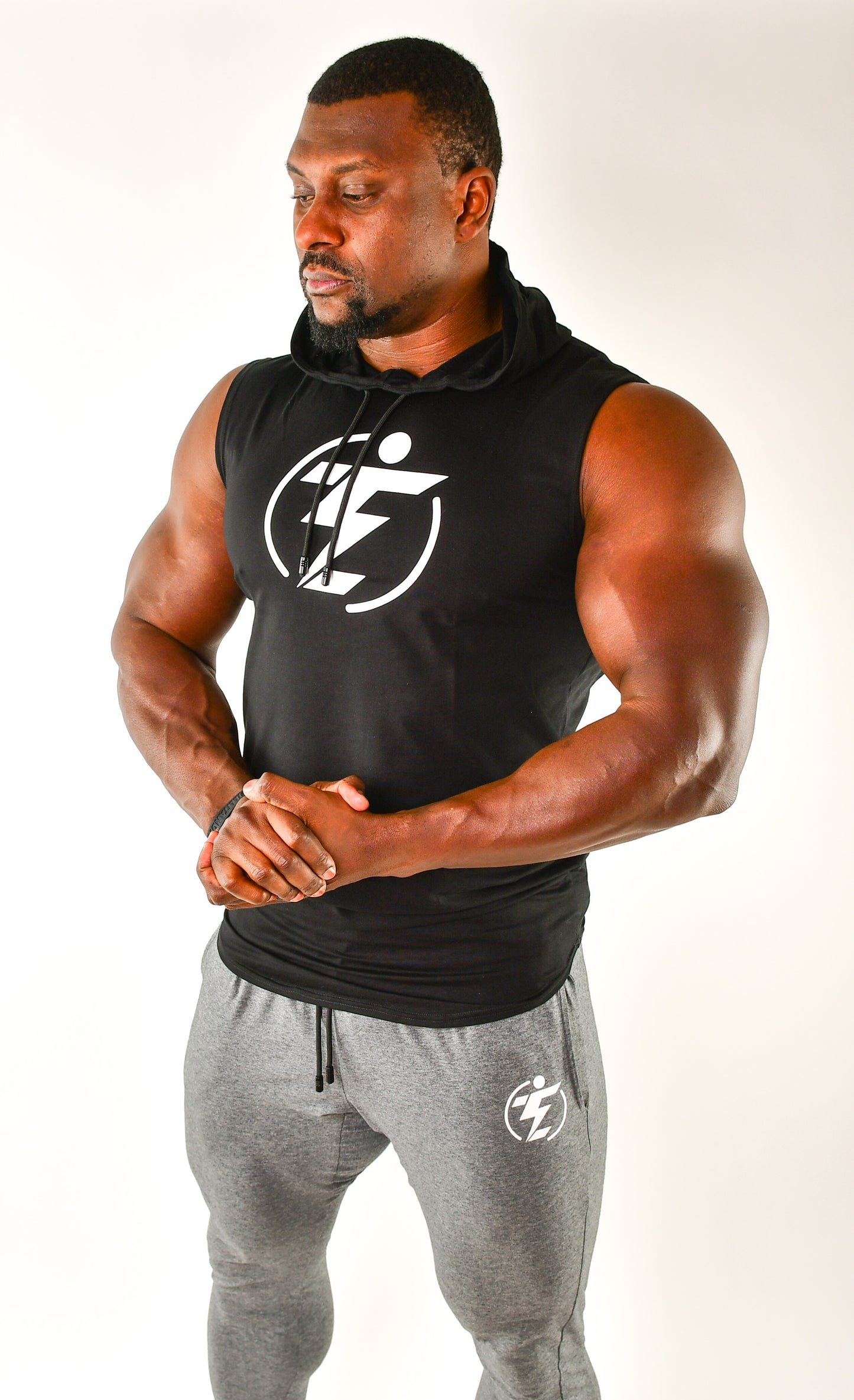 Man in black sleeveless hoodie and grey joggers with logo. Athletic wear.
