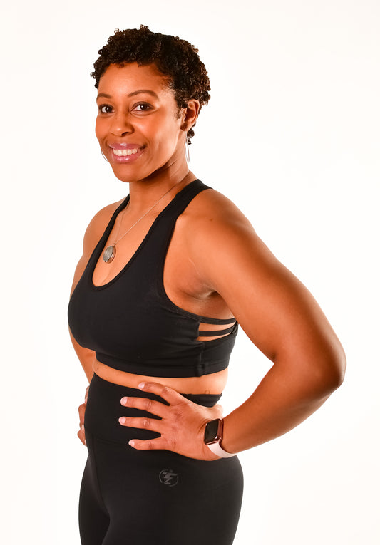 Woman in black sports bra and leggings with watch. Activewear product shot.