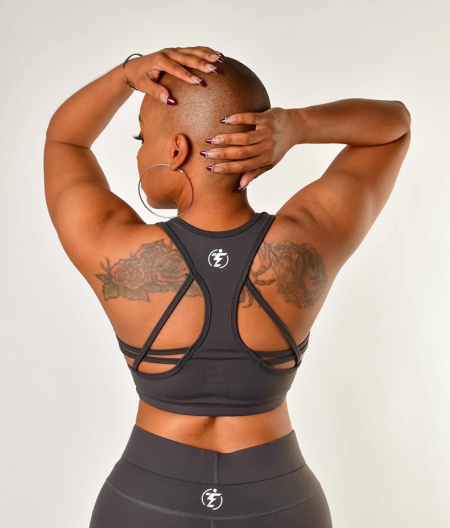 Back view of a woman in a gray sports bra and leggings set with a strappy back design.