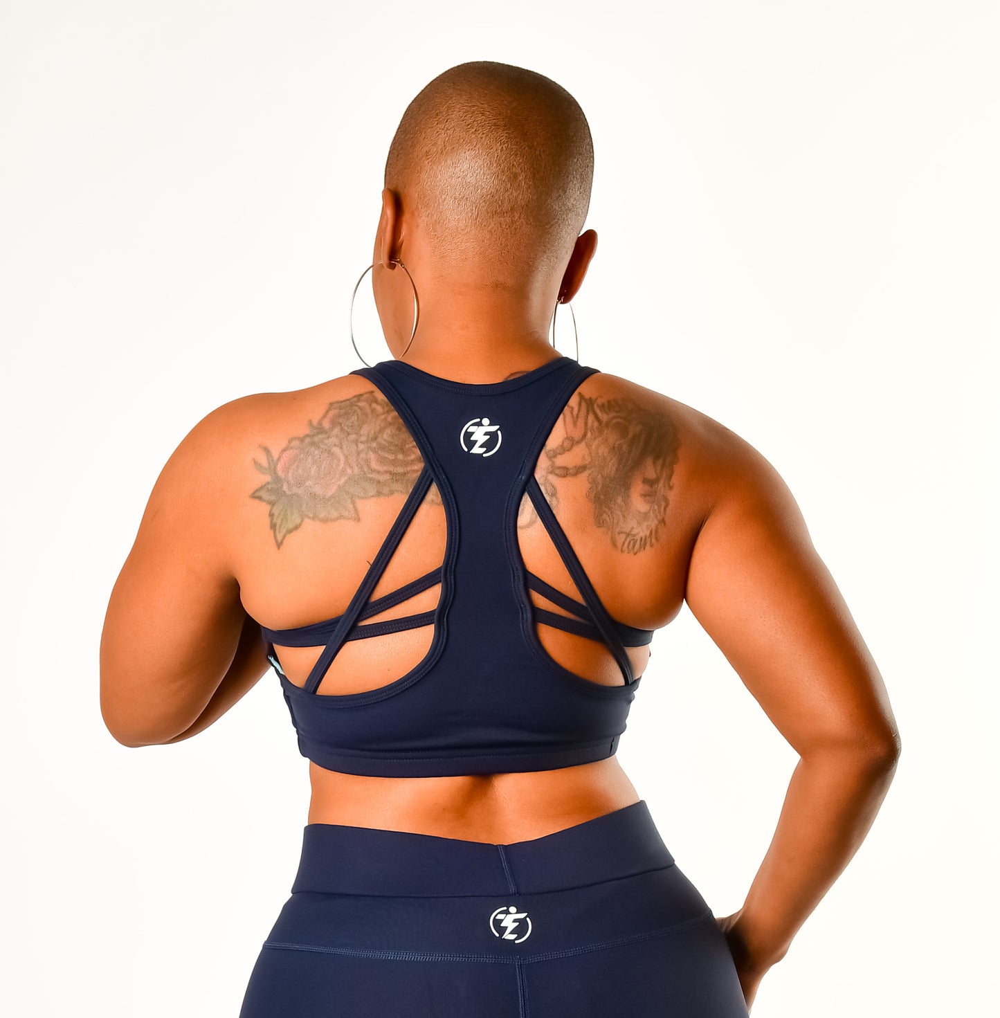 Back view of a woman in a navy blue strappy sports bra and leggings workout set.