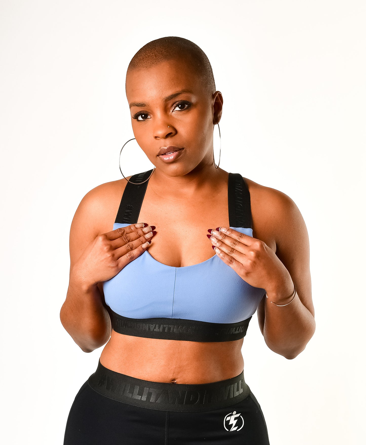 Woman wearing blue sports bra and black leggings with logo, fitness apparel.