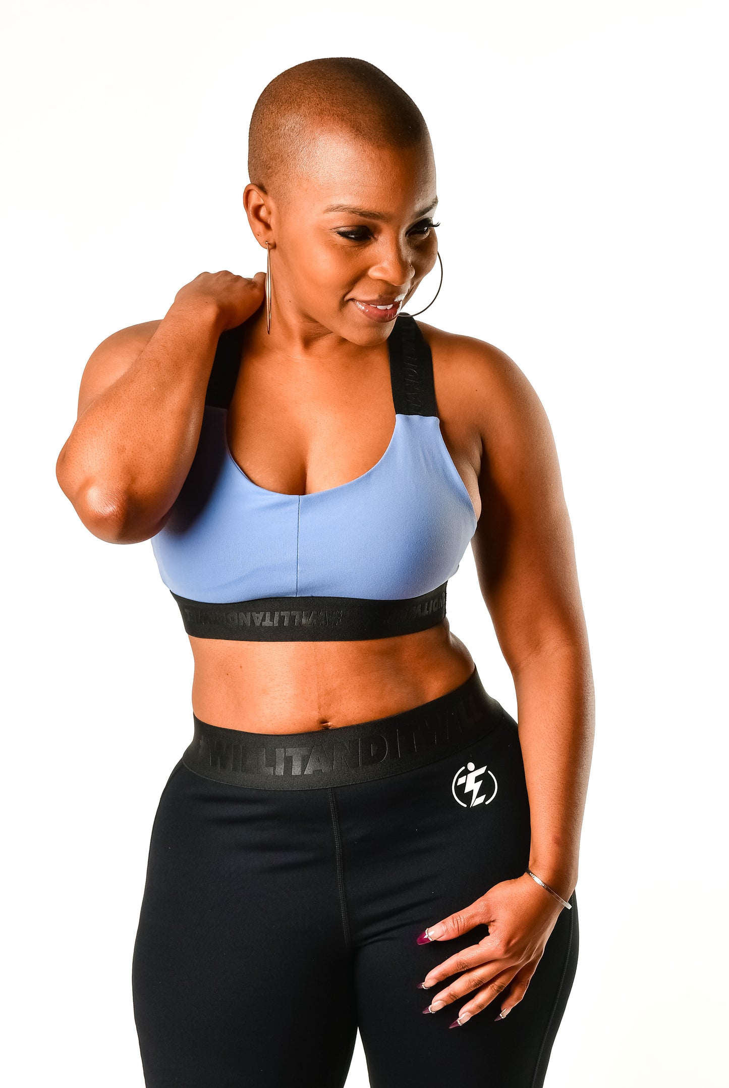 Woman in blue sports bra and black leggings activewear set, looking down.