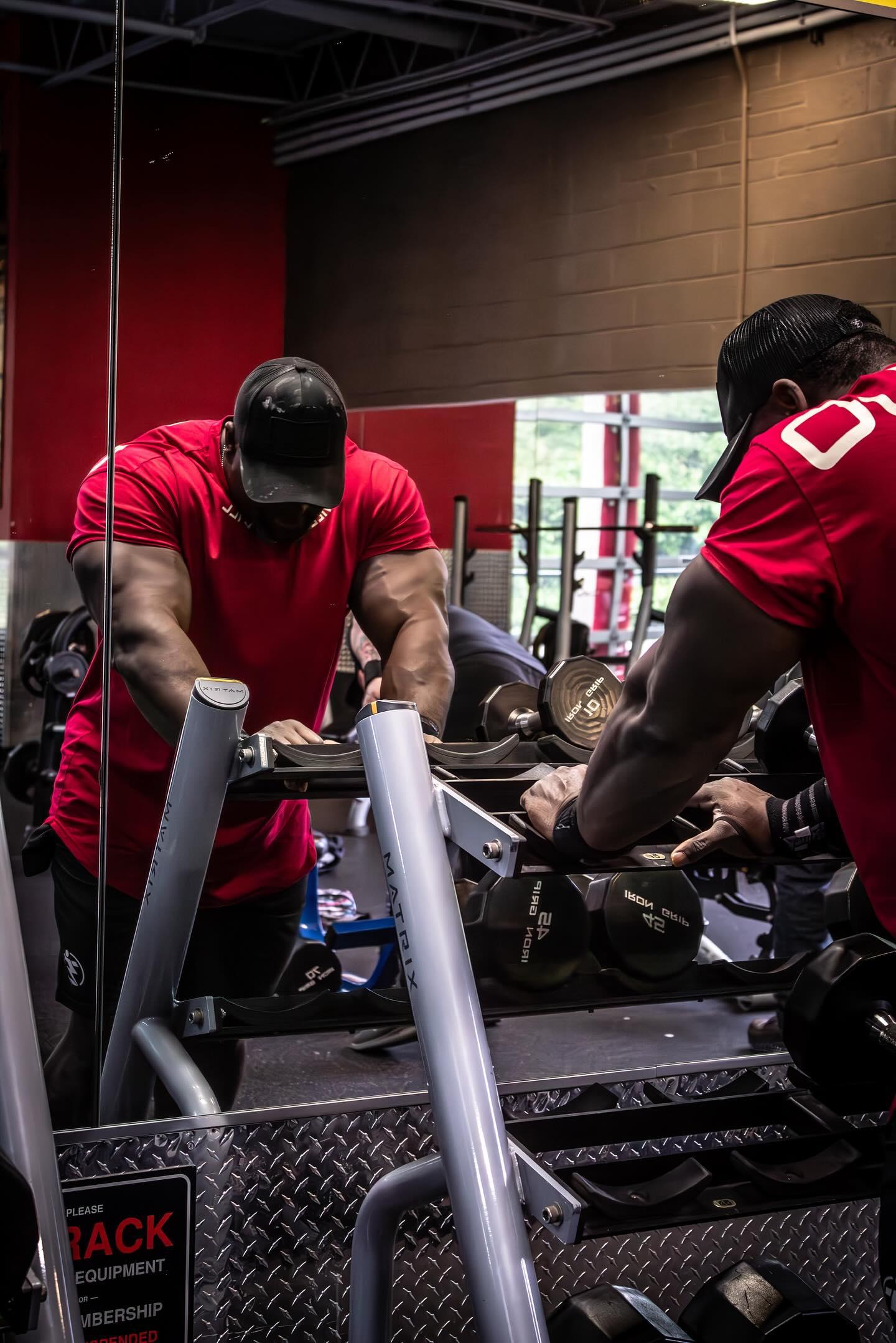 Man racks 42 lb dumbbells in a Matrix weight rack at the gym.