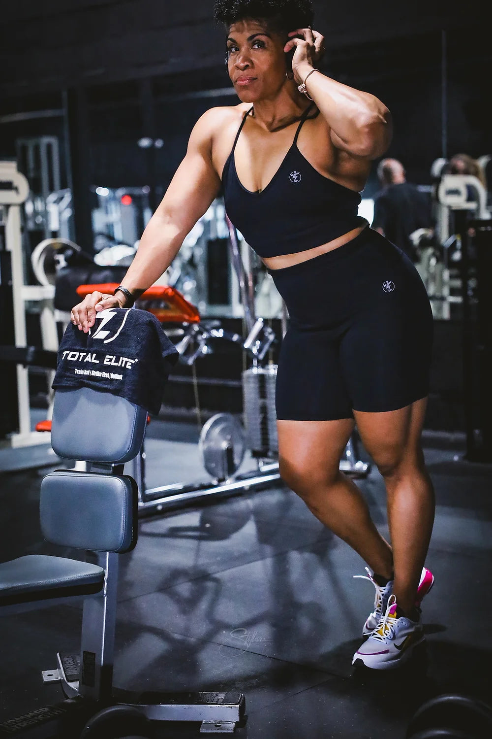 Woman in black workout set with sports bra and biker shorts at the gym.