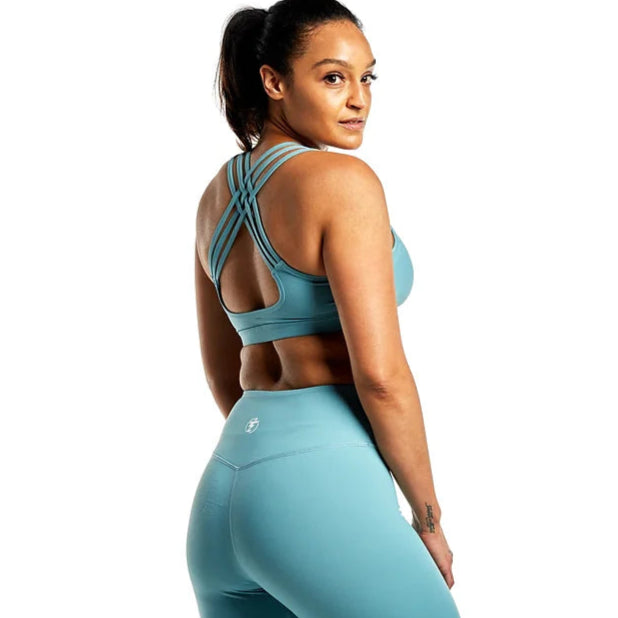 Woman wearing teal strappy sports bra and leggings workout set